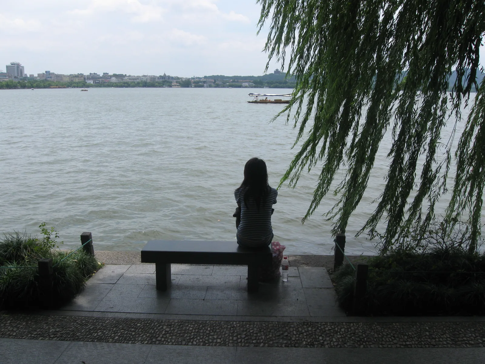 Bench and willow branches beside West Lake in Hangzhou
